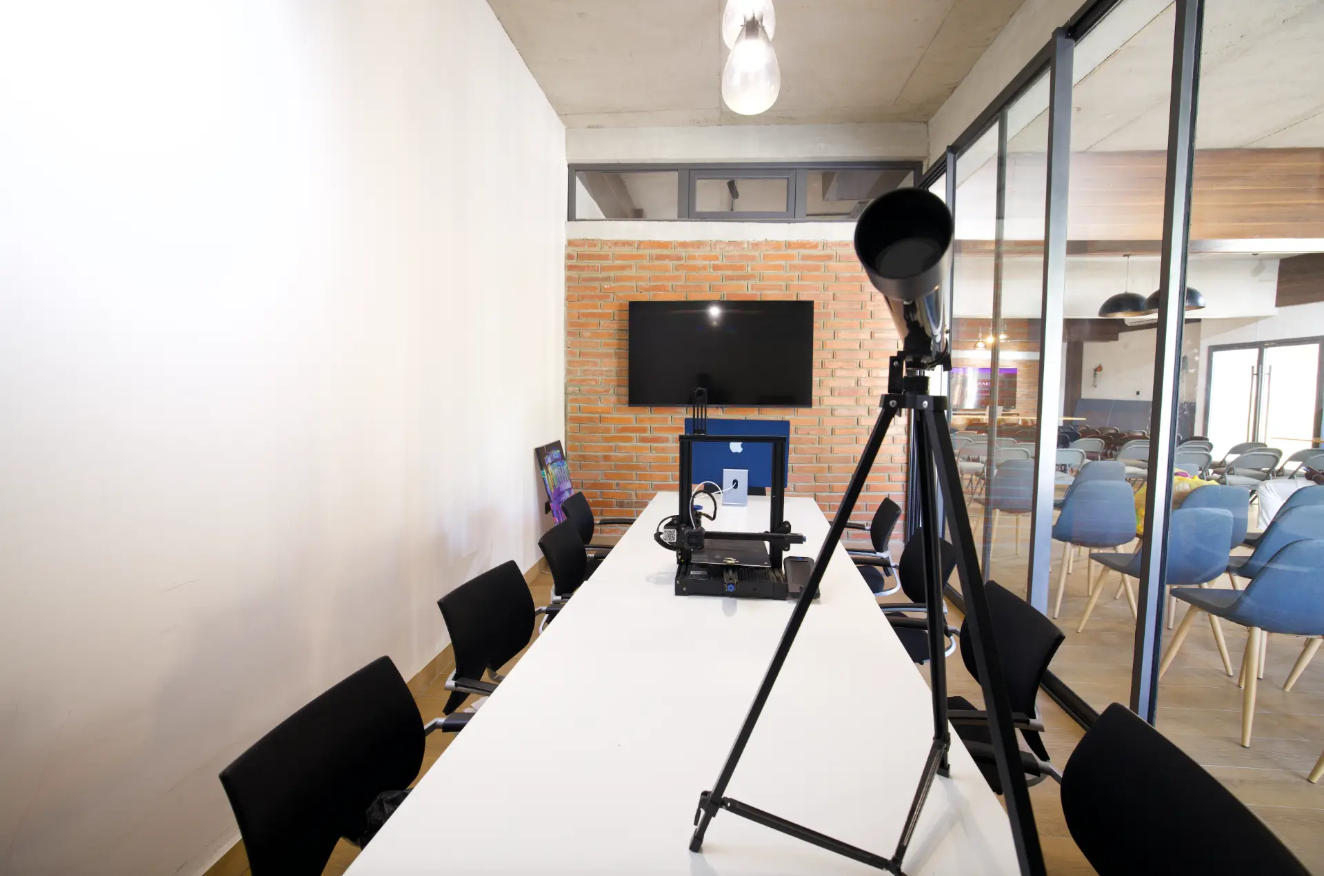 Salle de réunion vitrée avec table blanche et écran